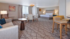 Een hotelkamer met een bed, twee stoelen, een tafel, een bank en een lamp.