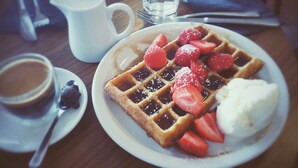 A plate with waffles, strawberries, and a scoop of ice cream. - Crowne Plaza Columbus North- Worthington by IHG (Columbus)
