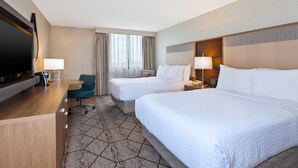 A hotel room with two beds, a desk with a flat-screen TV, a chair, and a large window with curtains. - Crowne Plaza Columbus North- Worthington by IHG (Columbus)