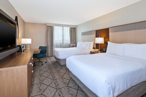 A hotel room with two beds, a desk with a flat-screen TV, a chair, and a large window with curtains. - Crowne Plaza Columbus North- Worthington by IHG (Columbus)