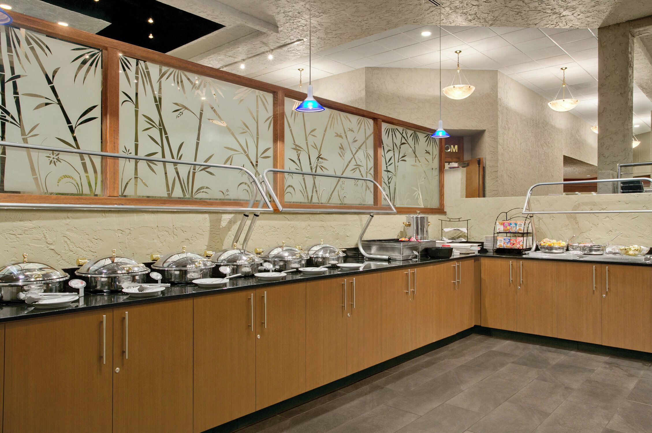 Montaje de buffet con estaciones de comida cubiertas, armarios de madera y piso de baldosas.