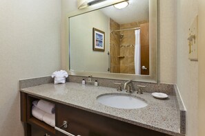 A bathroom with a granite countertop sink, a large mirror, and a towel rack. - Crowne Plaza Columbus North- Worthington by IHG (Columbus)