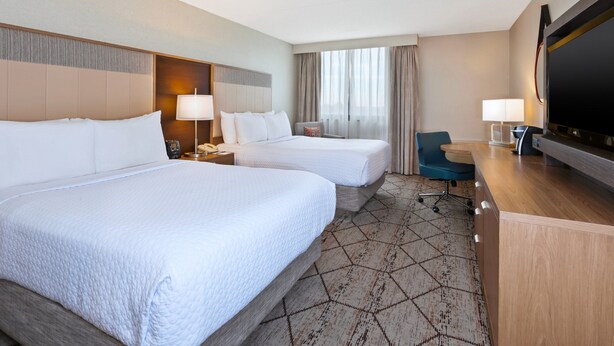 A hotel room with two beds, a desk, a TV, and a chair. - Crowne Plaza Columbus North- Worthington by IHG (Columbus)
