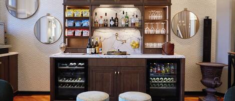 A bar area with wine bottles, glasses, and a marble countertop.