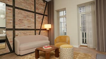 A living room with a brick wall, a sofa, a chair, a lamp, and a patterned ottoman.