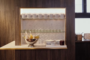 A breakfast bar with stacked plates, a fruit bowl, and various condiments.