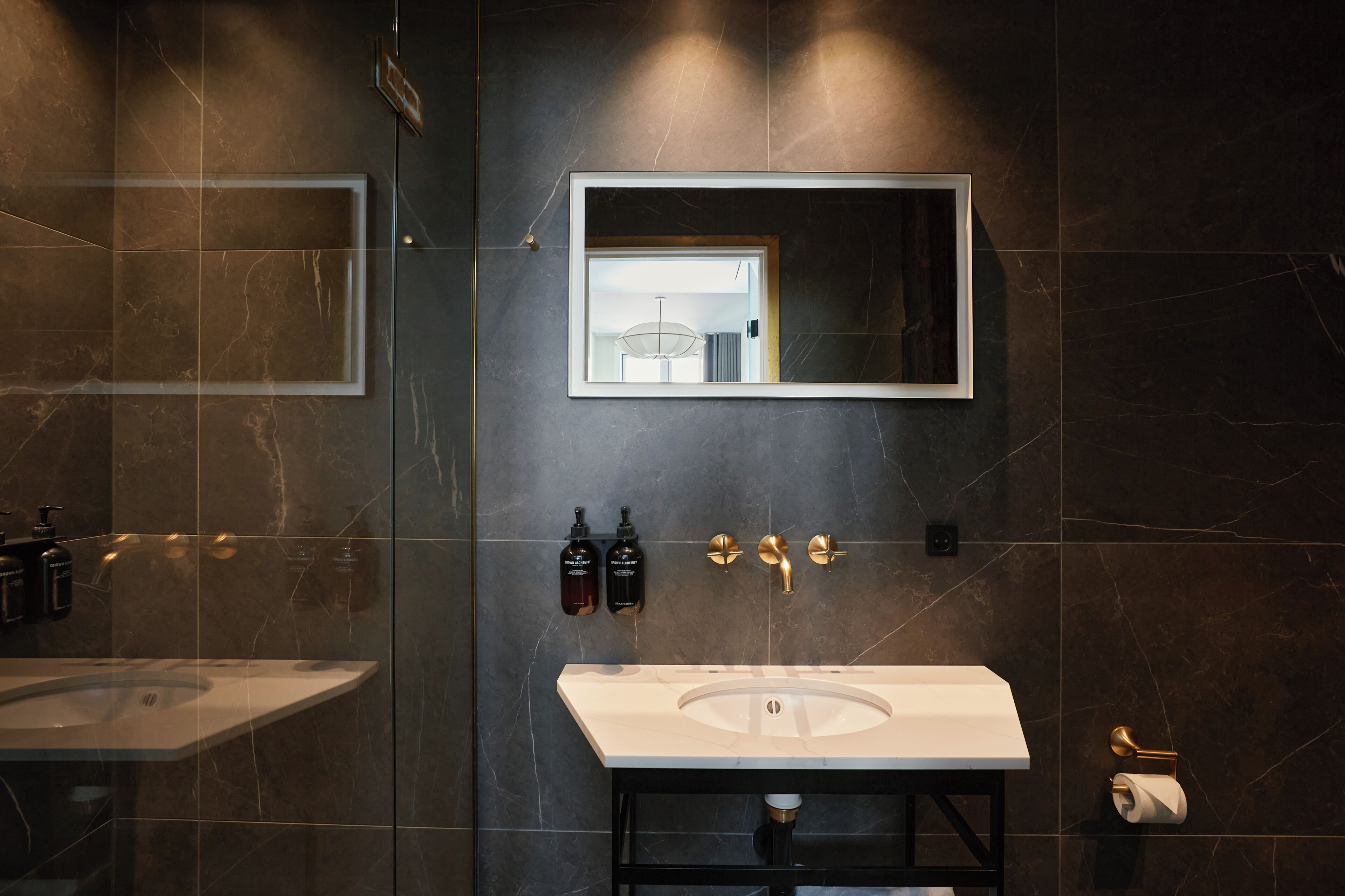 A modern bathroom with a large mirror, two sinks, and a toilet.