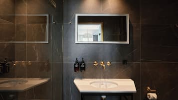 A modern bathroom with a large mirror, two sinks, and a toilet.