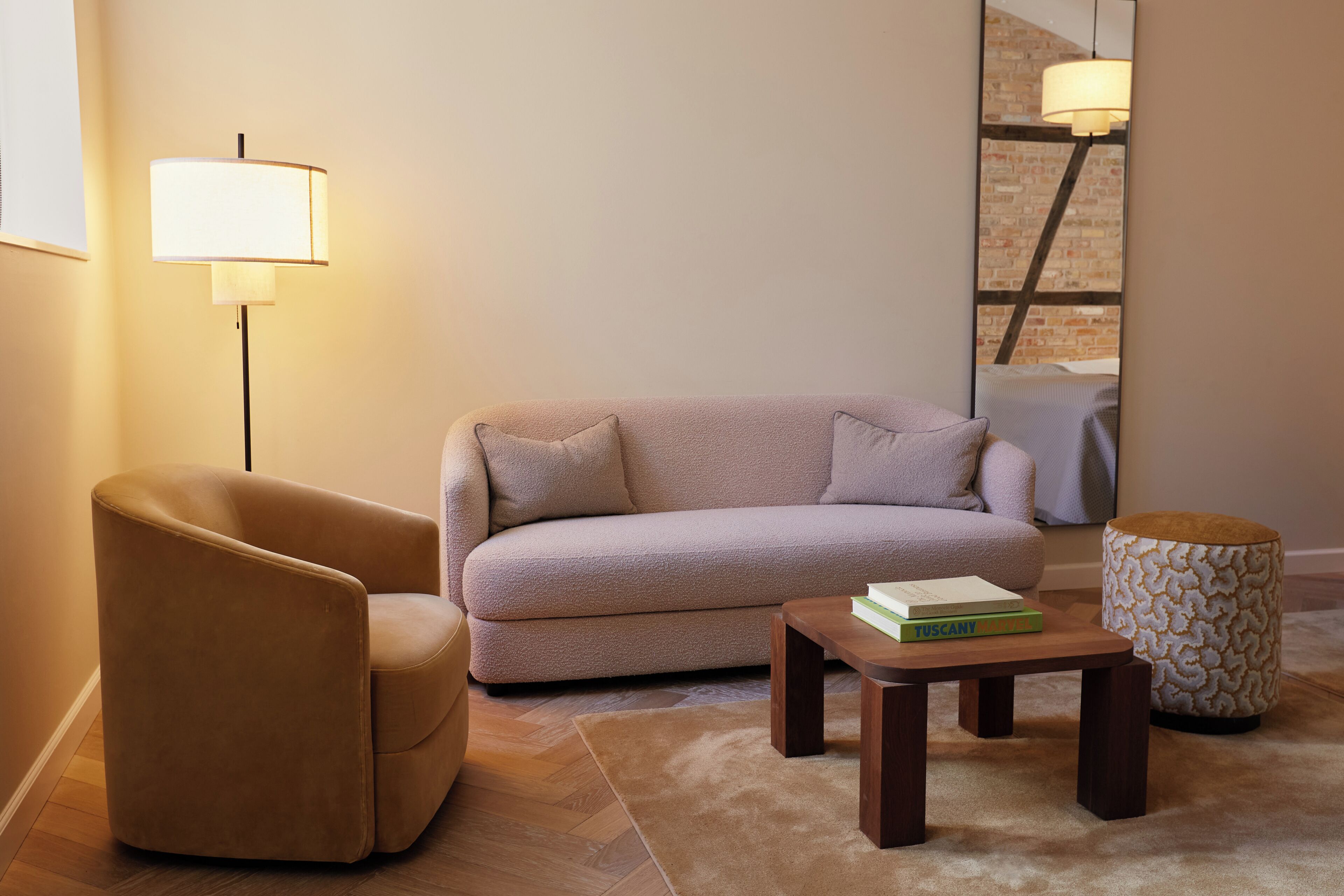 A modern living room with a sofa, armchair, coffee table, and a lamp.