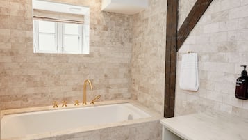Un baño con bañera, ventana y perchero.