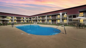 A hotel with a swimming pool, outdoor seating, and a multi-story building with balconies. - Red Roof Inn Kingsport (Kingsport)