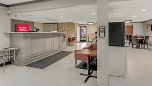 A hotel lobby with a reception desk, a seating area with a red couch, and a dining area with tables and chairs. - Red Roof Inn Kingsport (Kingsport)