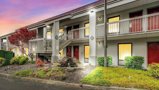 A multi-story hotel with a central staircase, balconies, and a landscaped garden with a small water feature. - Red Roof Inn Kingsport (Kingsport)