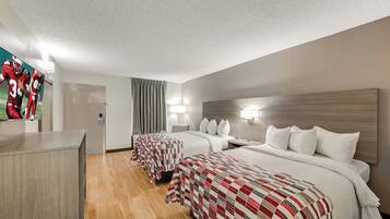 A hotel room with two beds, a desk, and a mirror.