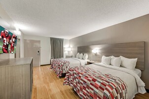 Una habitación de hotel con dos camas, un escritorio y un espejo.
