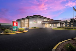 A hotel with a large parking lot, a Red Roof Inn sign, and Home Towne Studios.