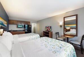 Une chambre d’hôtel avec deux lits, une kitchenette, une télévision et un miroir.