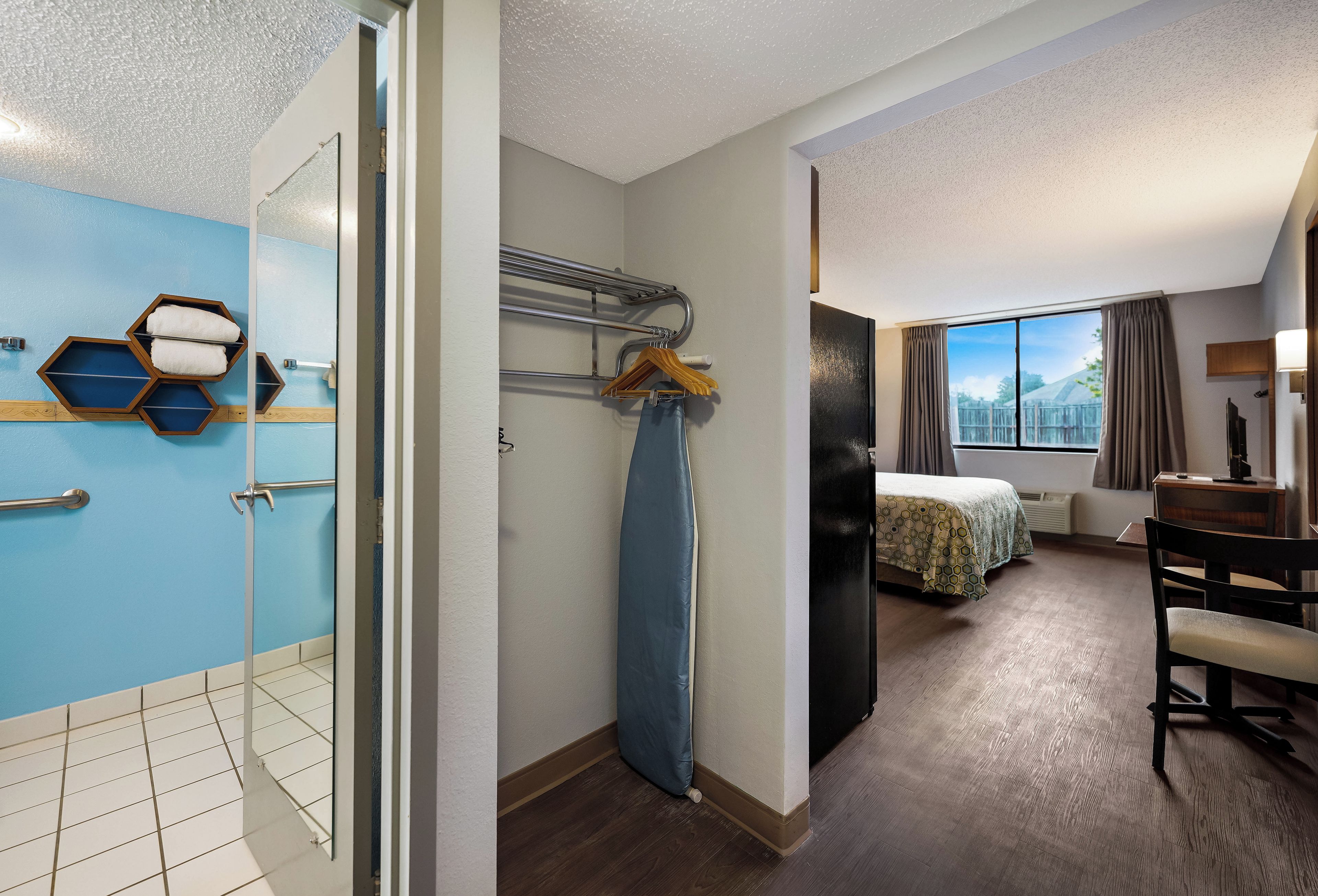 A hotel room with a shower, a bed, a desk, and a view of the outdoors.