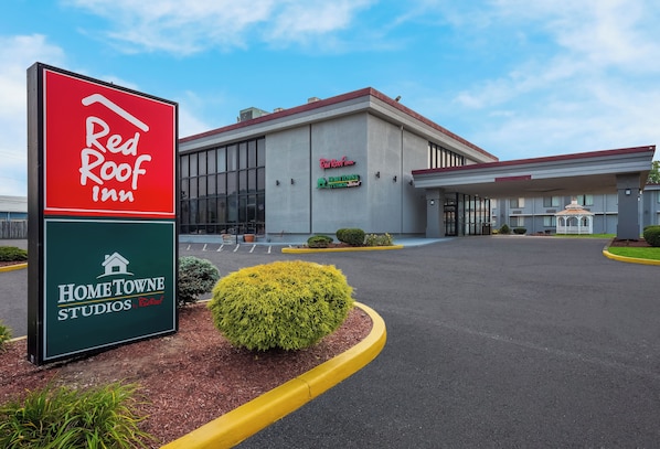 A Red Roof Inn with a large sign, a covered parking area, and a building entrance.