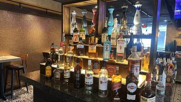 Zona de bar con una variedad de botellas de licores y una pantalla de televisión al fondo.