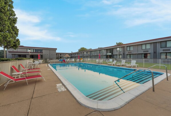 Relax by the pool surrounded by lounge chairs and a safety handrail.