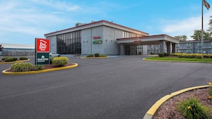 A hotel with a large entrance, a Red Roof Inn sign, and a Home Town Studios sign.