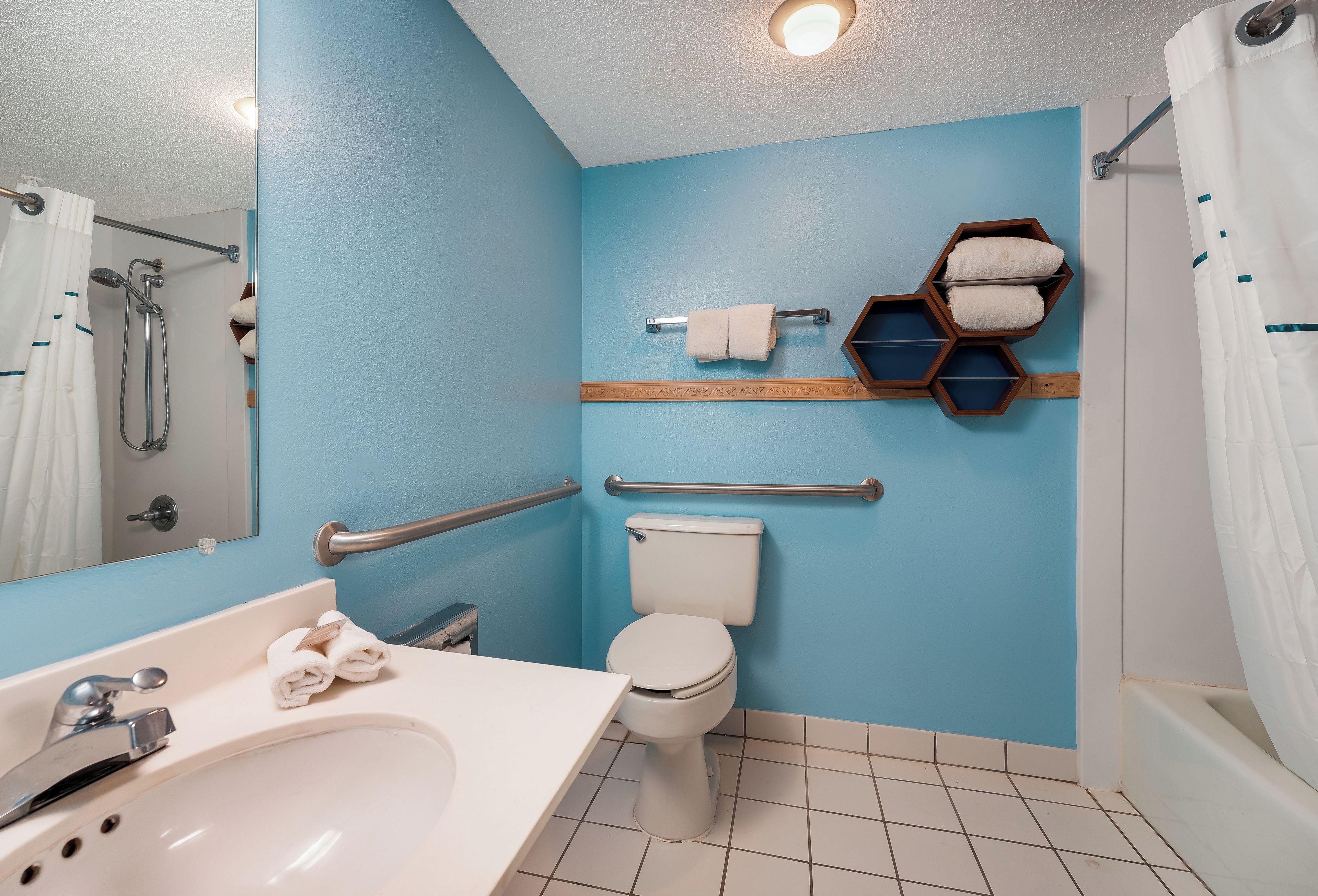 A bathroom with a white sink, a toilet, a shower, and a towel rack.