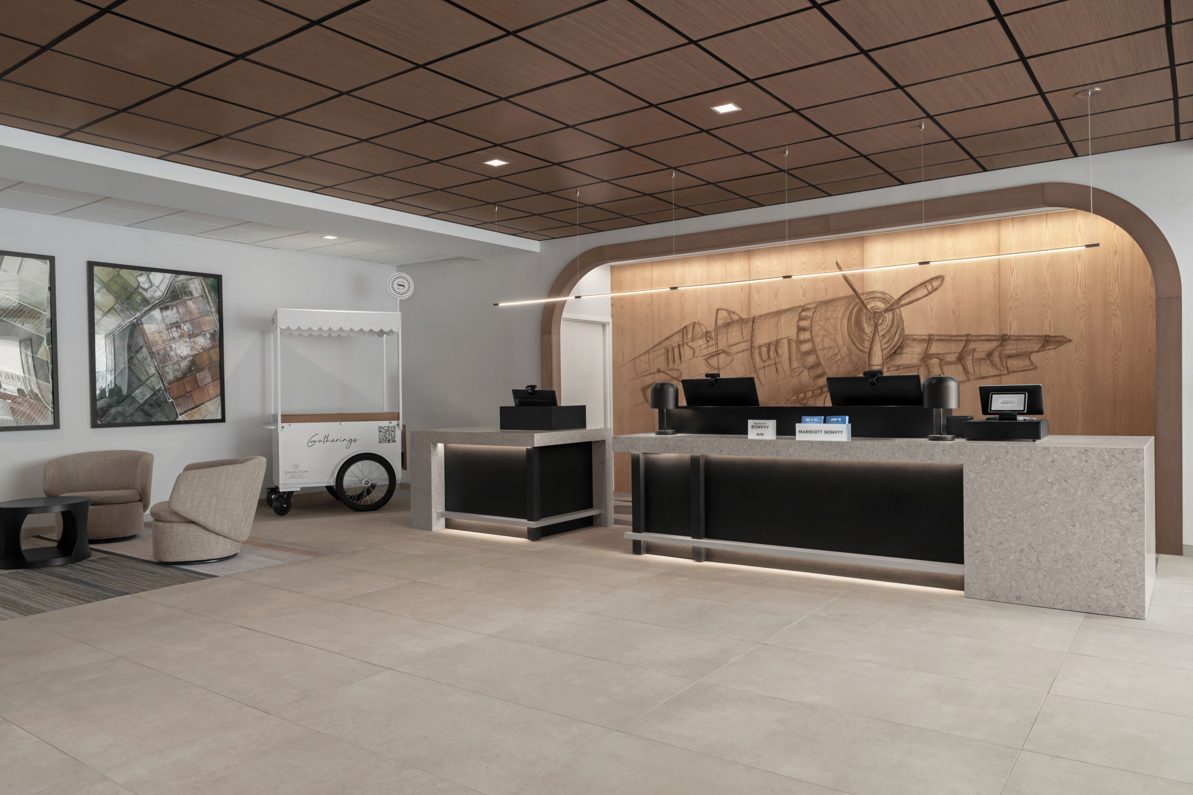 A hotel reception area with a modern design, featuring a reception desk, seating area, and artwork on the walls.