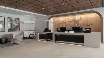 A hotel reception area with a modern design, featuring a reception desk, seating area, and artwork on the walls.