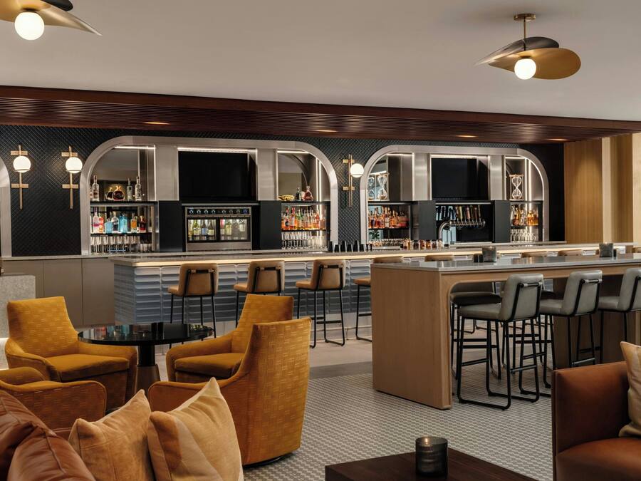 A bar area with a counter, bar stools, and a seating area with sofas and chairs.