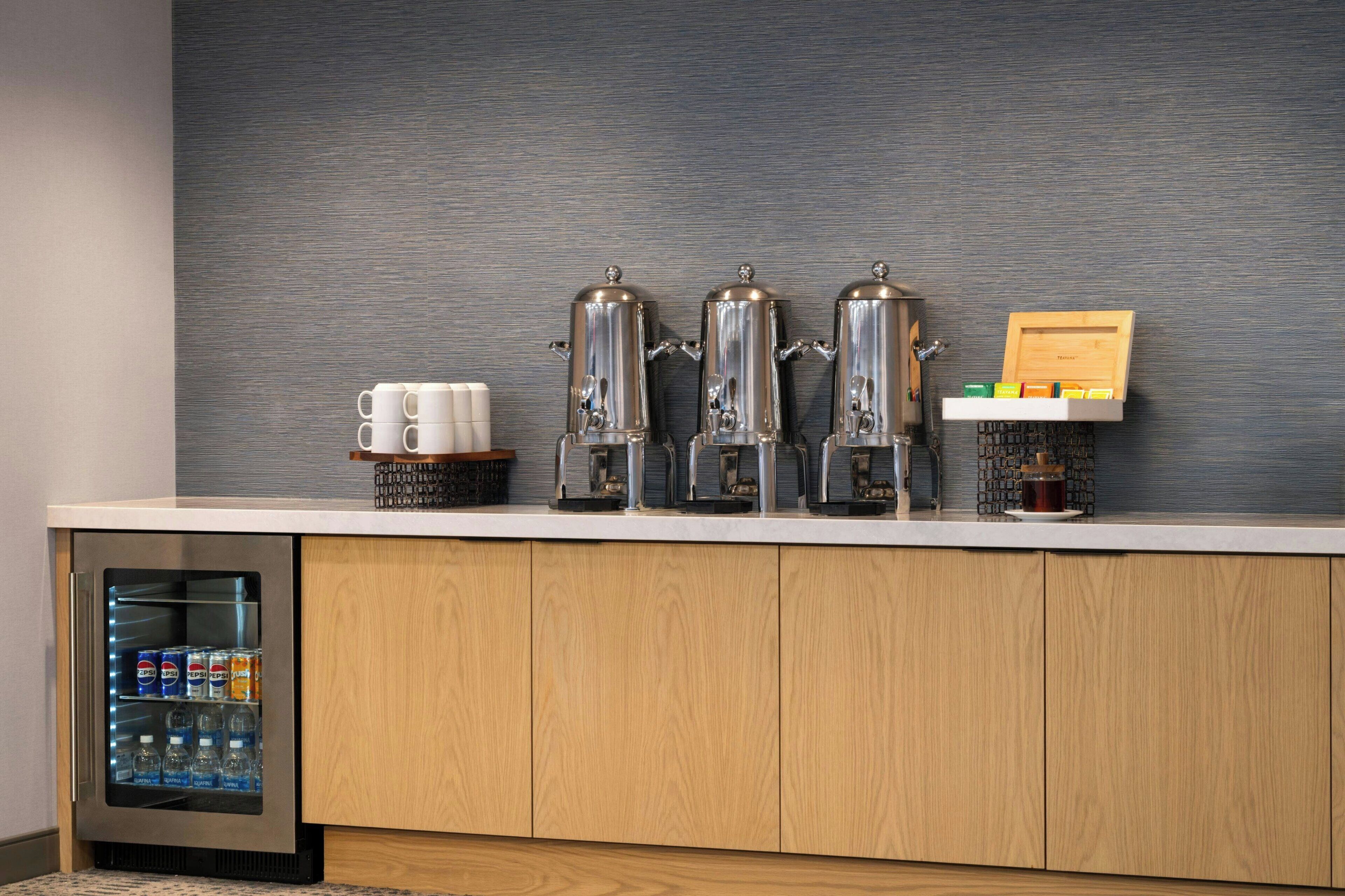 Ein Hotelzimmer mit Minibar, einer Kaffeestation und einem mit Getränken gefüllten Kühlschrank.