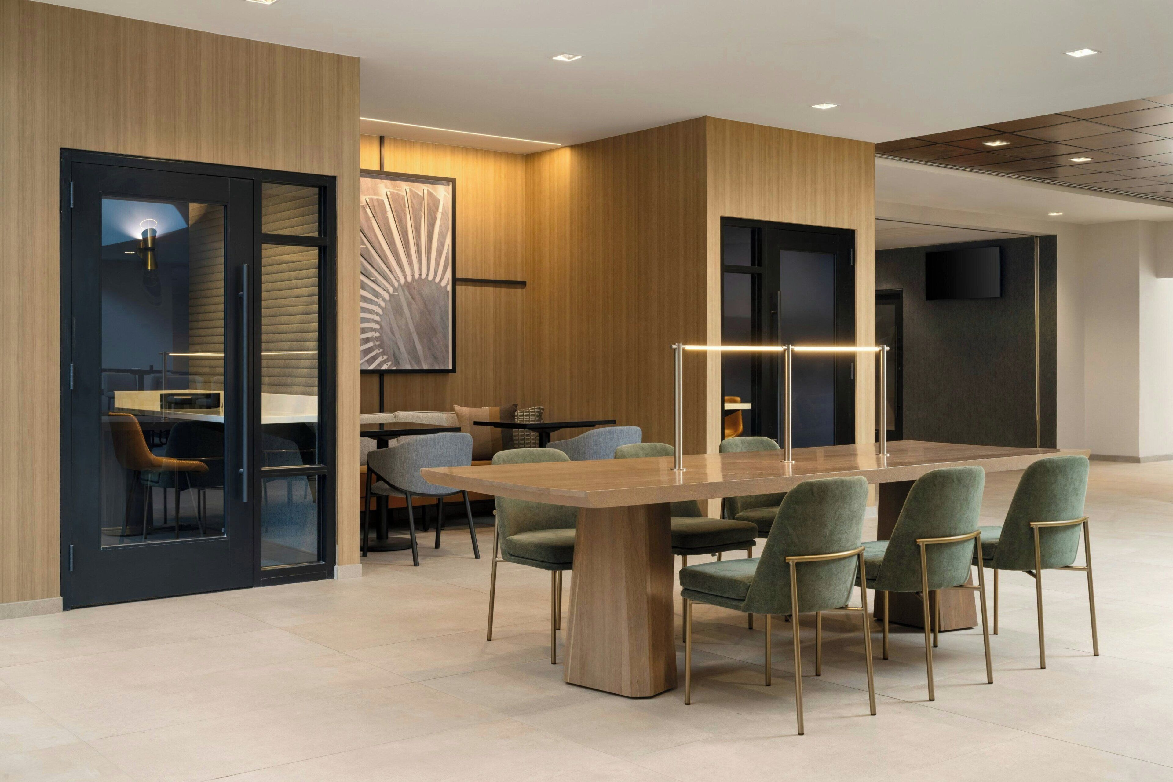 A modern dining area with a wooden table and green upholstered chairs.