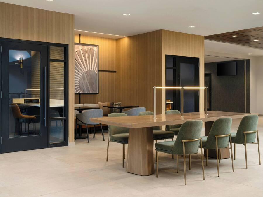 Un comedor moderno con una mesa de madera y sillas tapizadas en verde.