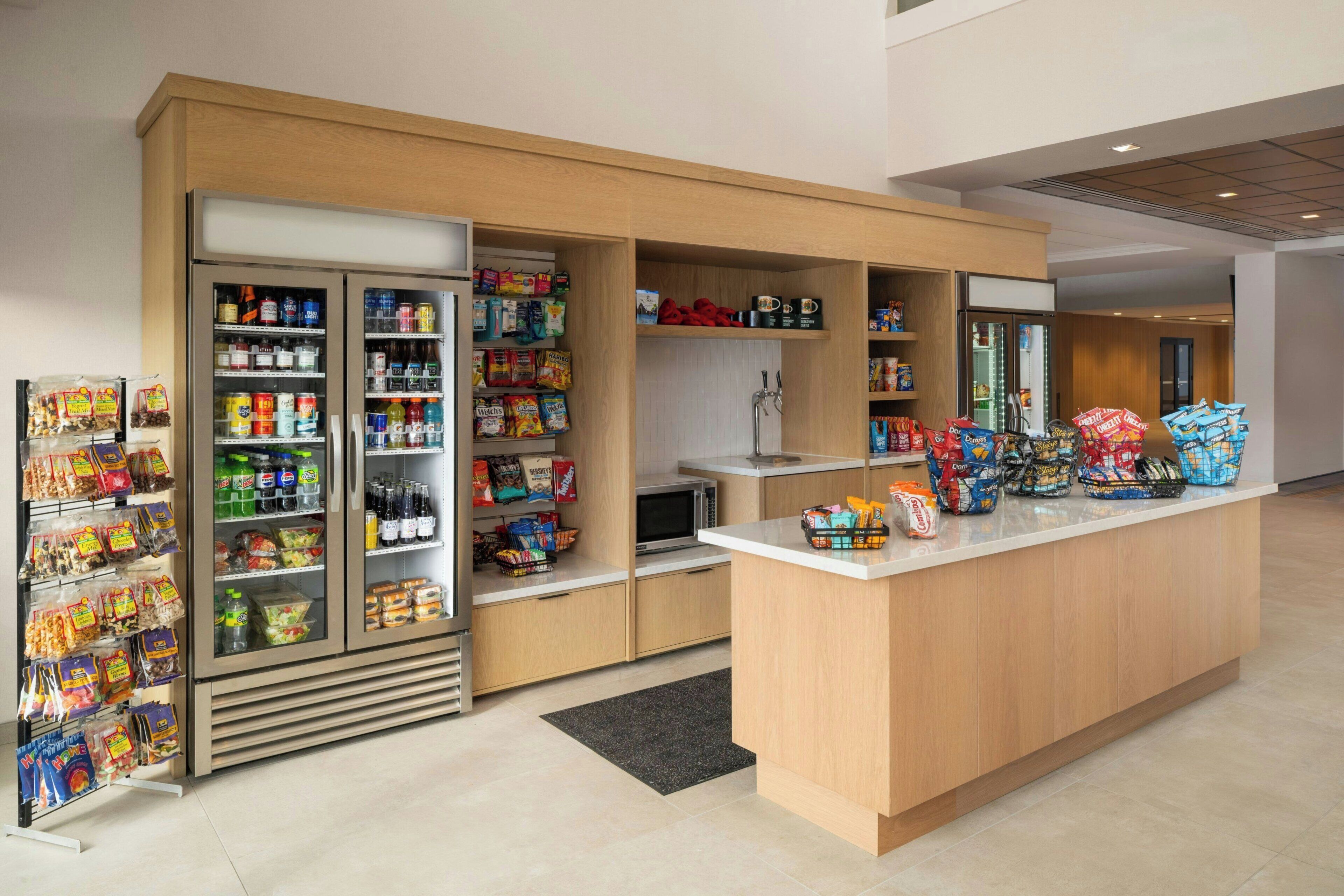 A self-service snack bar with refrigerated and non-refrigerated shelves stocked with various snacks, drinks, and packaged foods.