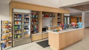 A self-service snack bar with refrigerated and non-refrigerated shelves stocked with various snacks, drinks, and packaged foods.