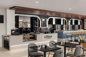 A modern cafe with a counter, seating area, and a display case.