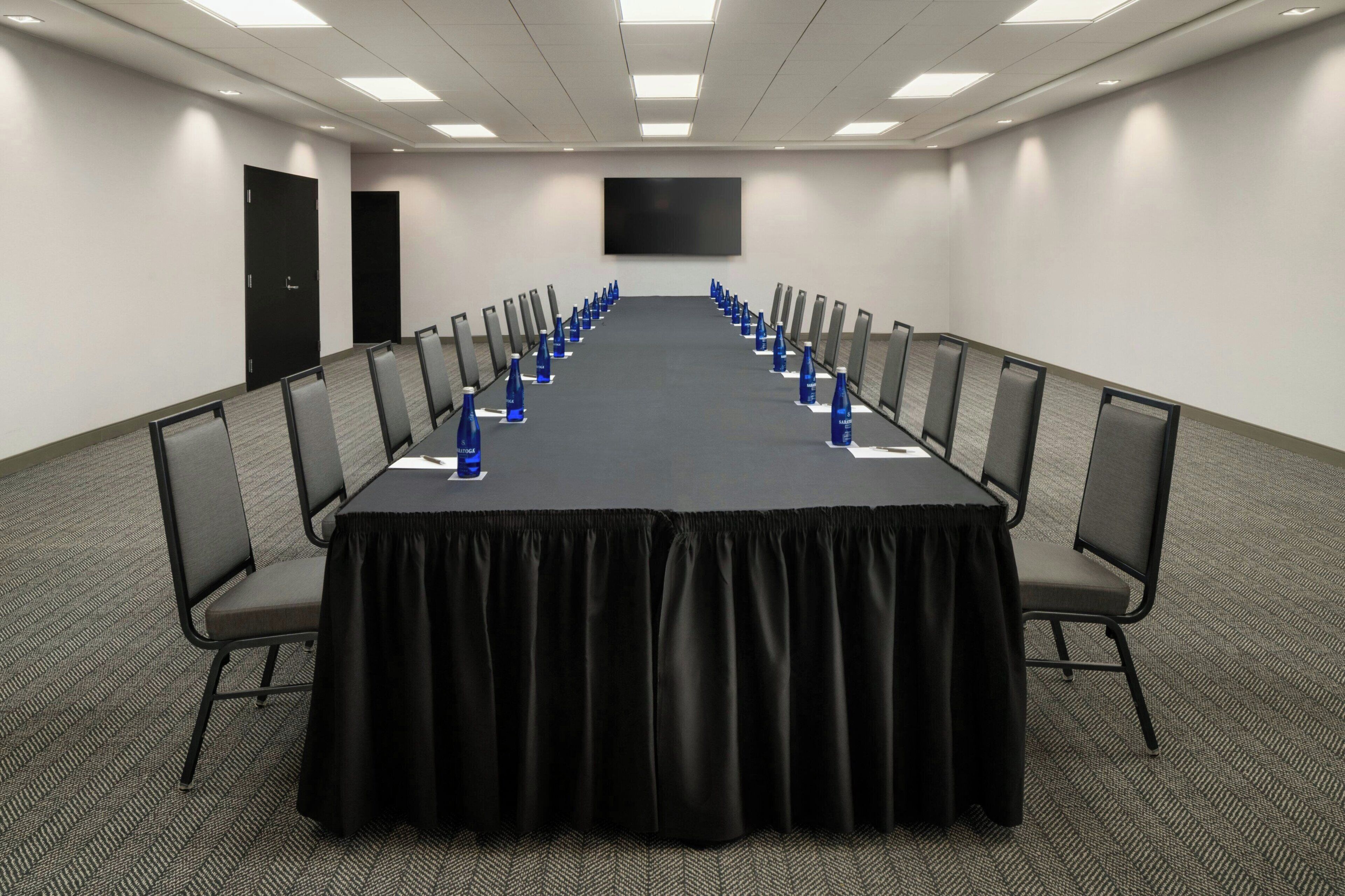 A conference room with a long table, chairs, and water bottles.