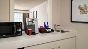 Eine Hotelküche mit Mikrowelle, Kaffeemaschine und Spüle.
