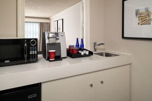 Une kitchenette d’hôtel équipée d’un four à micro-ondes, d’une machine à café et d’un évier.
