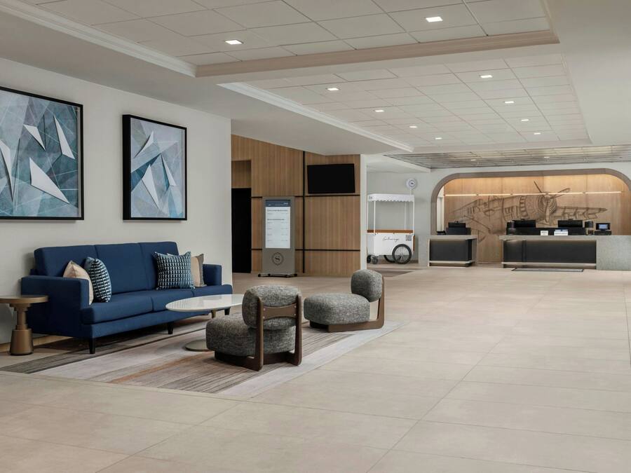 Un hall d’entrée moderne avec un canapé bleu, deux fauteuils, une table basse et un comptoir d’accueil.