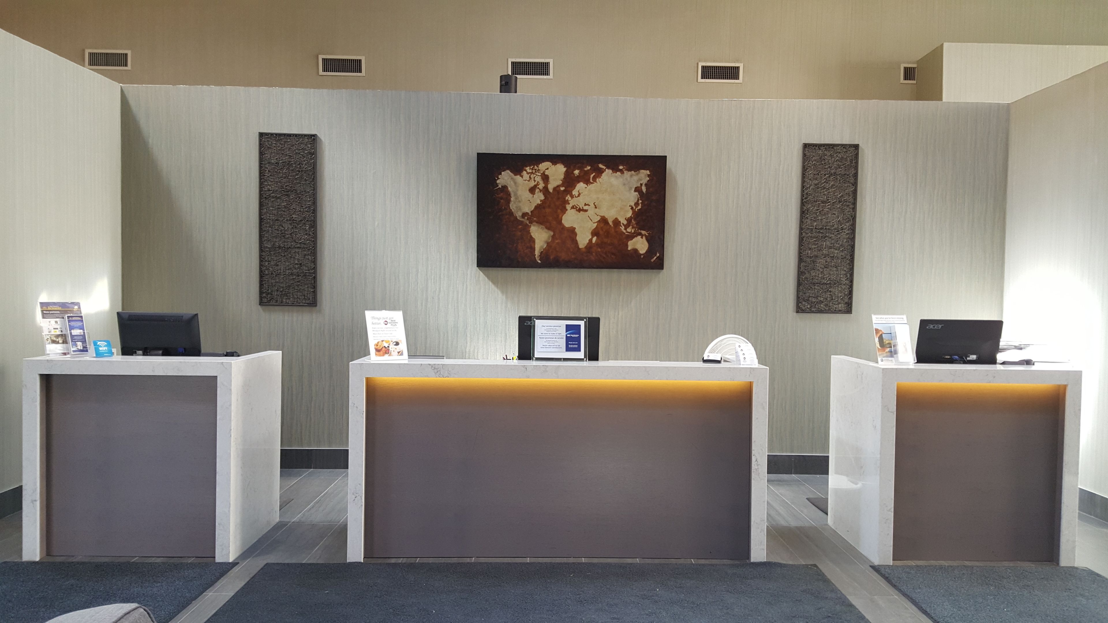 A reception desk area with three desks, a world map on the wall, and a sign with information.