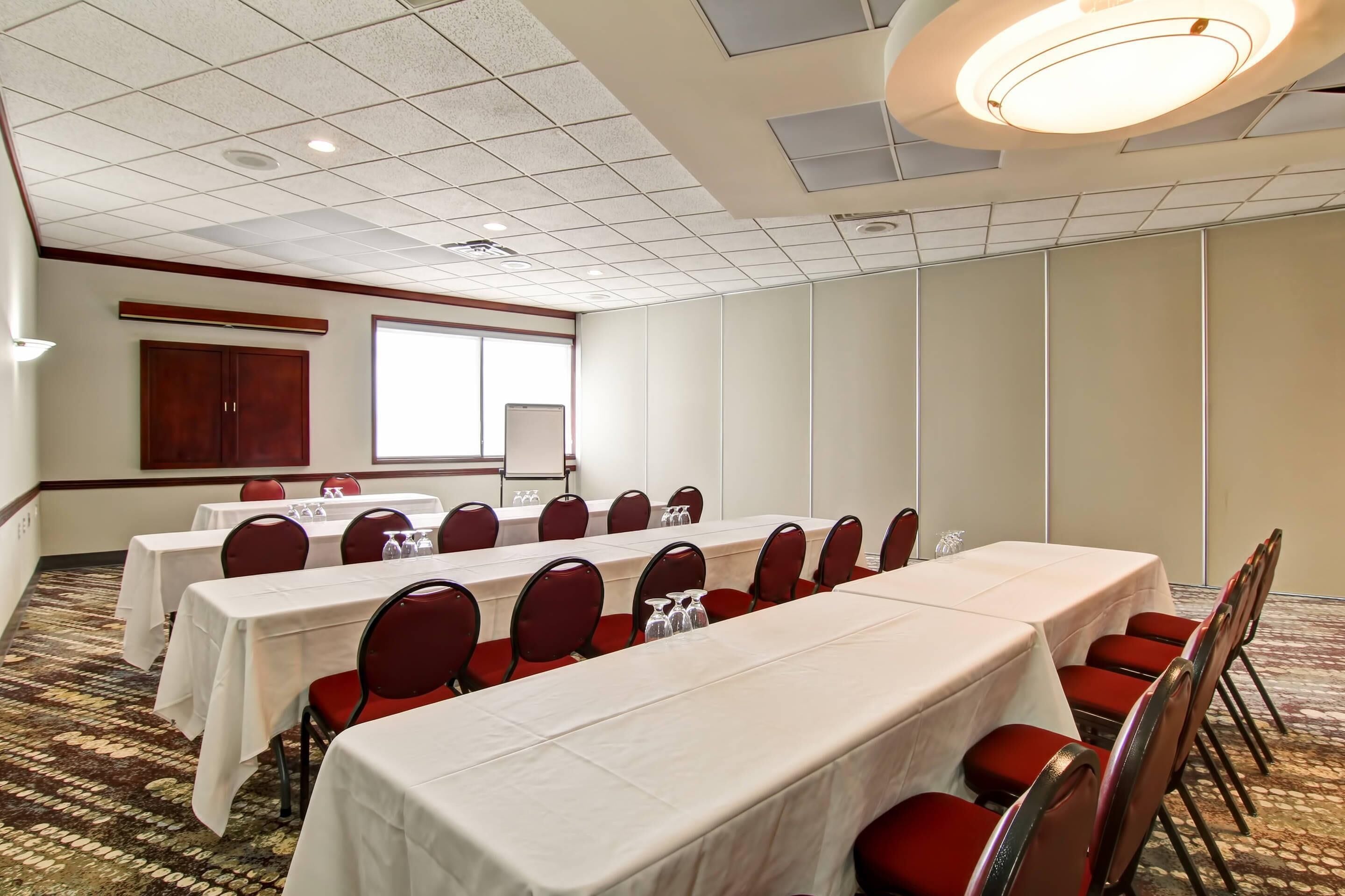 Una sala de conferencias con varias mesas, sillas y suelo alfombrado.