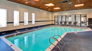Una piscina interior con techo de madera, paredes de azulejos y ventanas amplias.