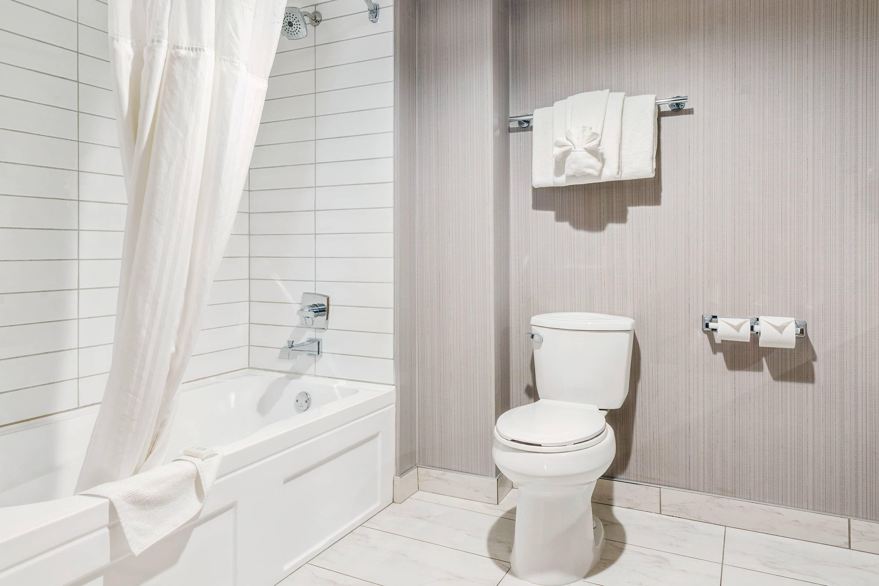Un baño moderno con bañera, inodoro y cortina de ducha.