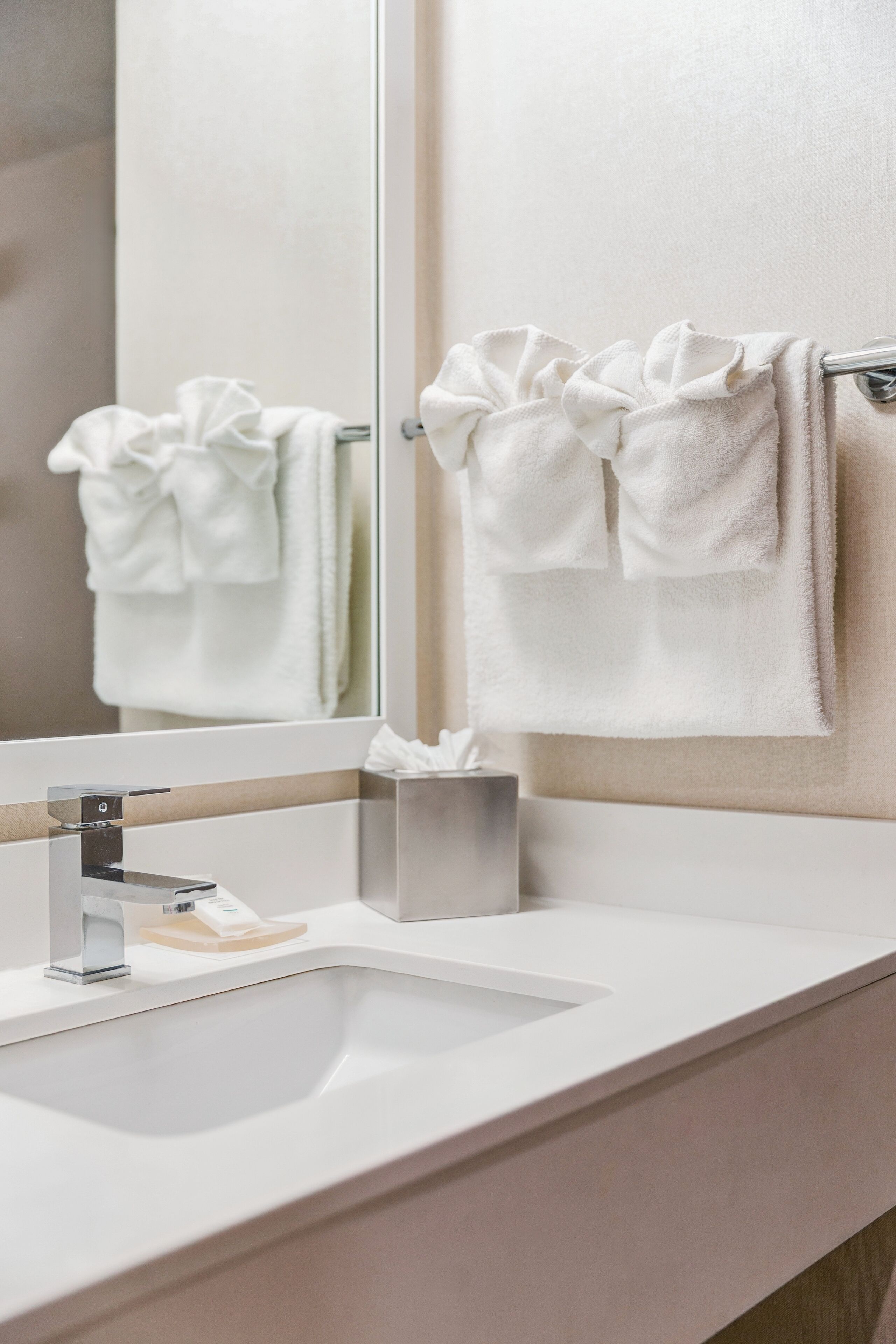 Une salle de bain avec un lavabo blanc, un miroir et un porte-serviettes avec deux serviettes.