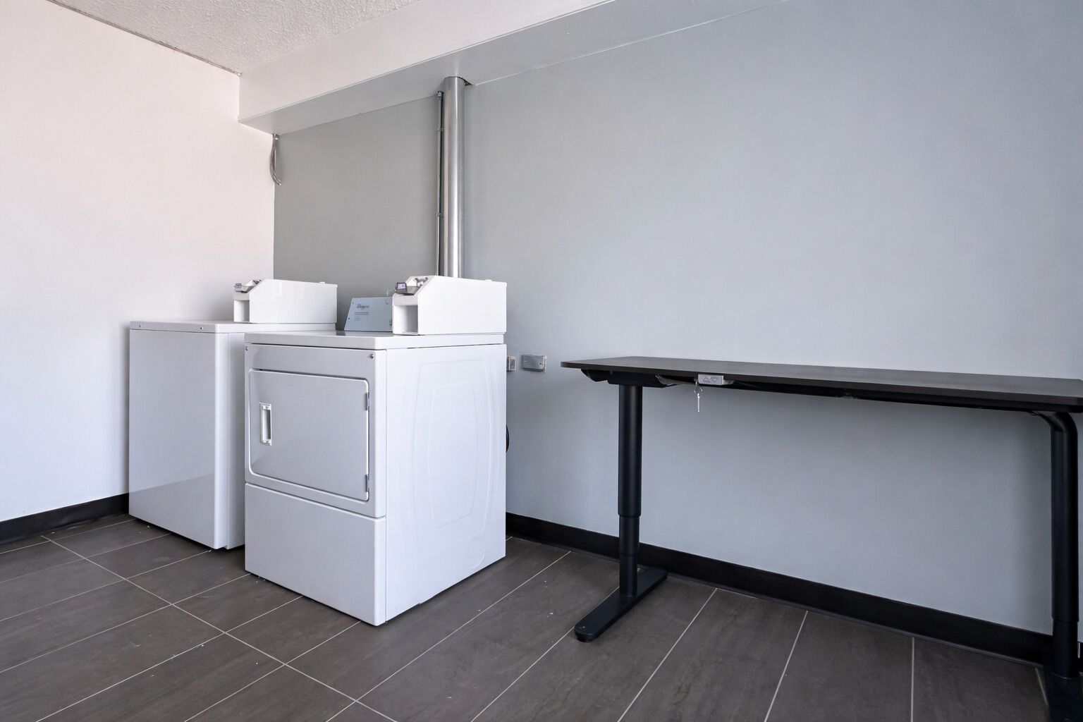 A compact room with a washing machine and a small table against a plain wall.