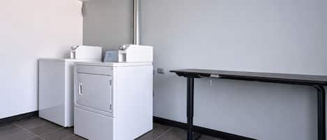 A compact room with a washing machine and a small table against a plain wall.