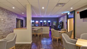 Un espacio interior moderno con una zona de recepción, máquinas de juegos y asientos para los huéspedes.