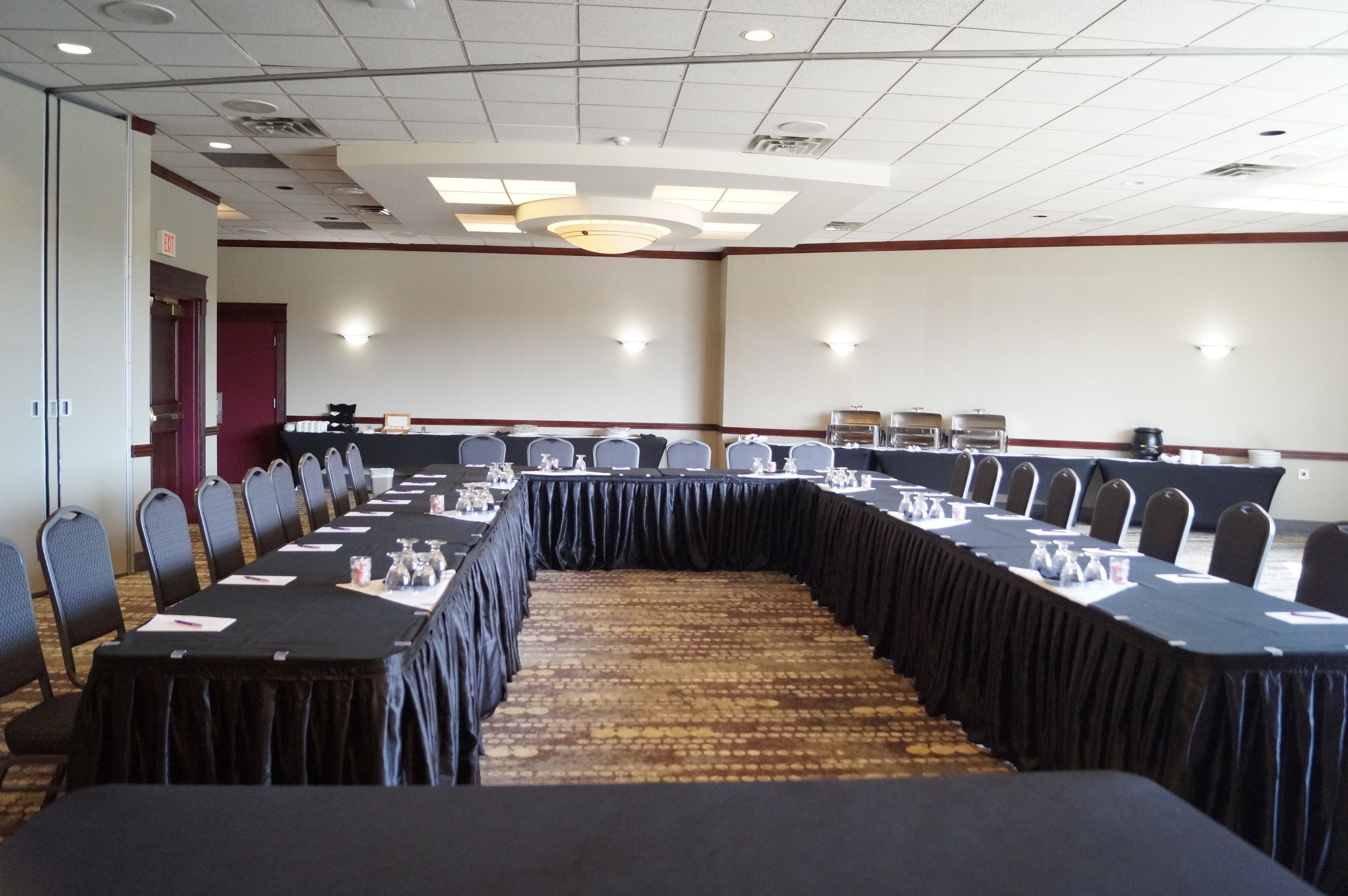 A conference room with a long table, chairs, and a carpeted floor.