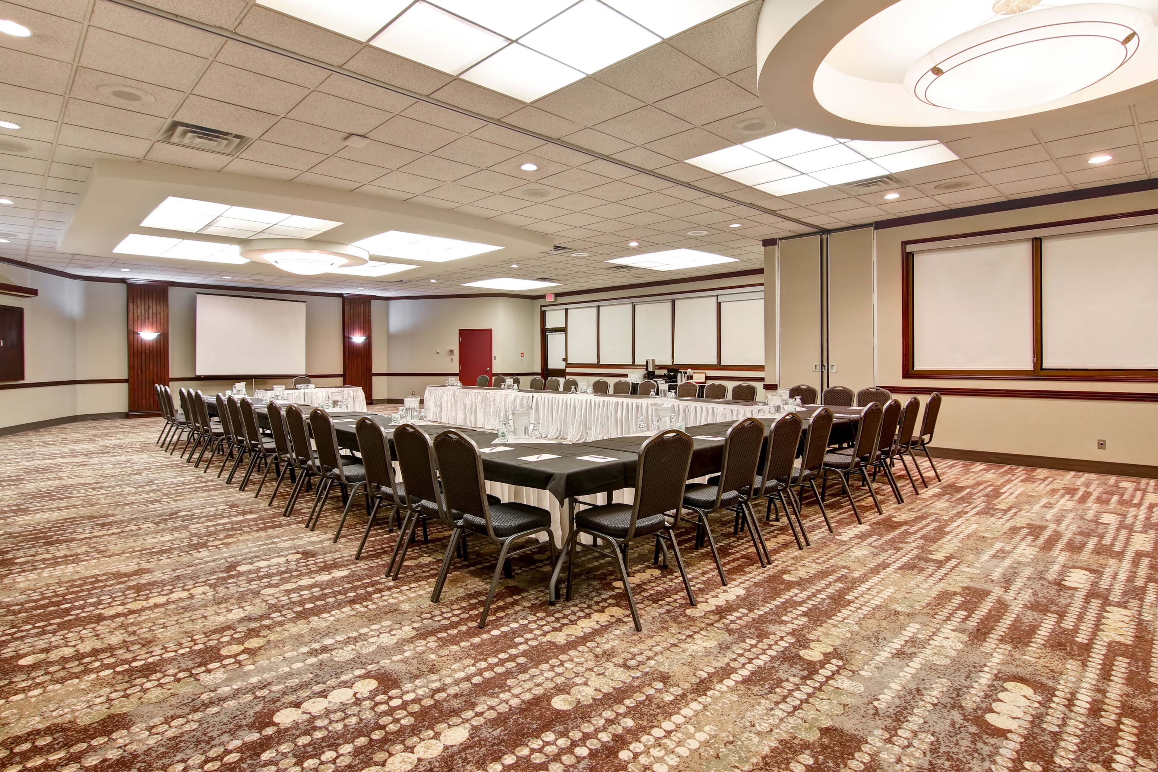 A conference room with a large table, chairs, and a carpeted floor.
